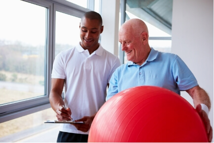 A physiotherapist showing a patient how to use a ball for treatment.